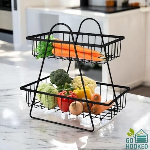 GoHooked black metal 2-tier fruit basket with carrots, broccoli, cauliflower, cabbage, peppers, and onions on a marble countertop.