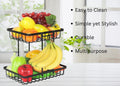 GoHooked black metal 2-tier fruit basket organizer filled with various fruits and vegetables on a white table.