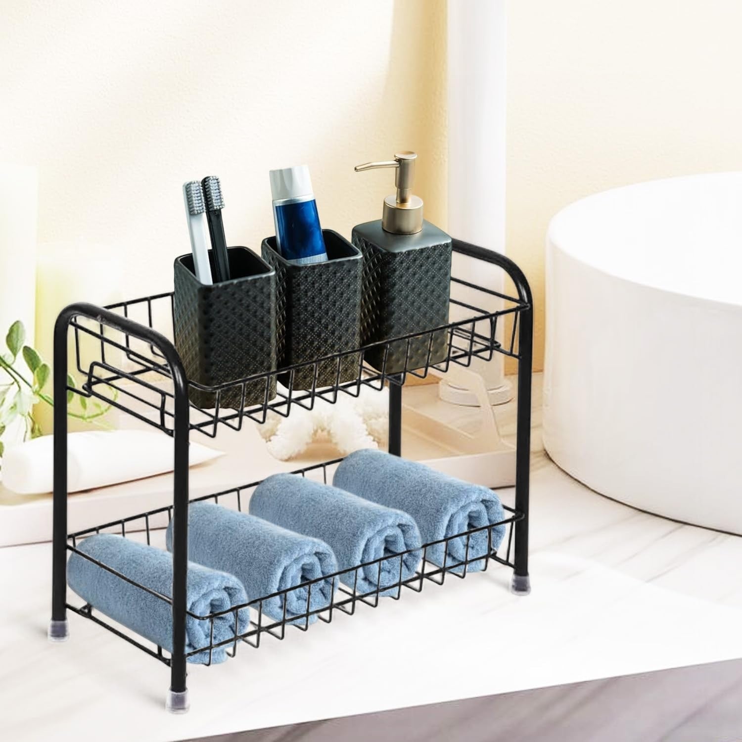 Go Hooked black 2-tier iron countertop organizer with diamond-patterned containers holding toothbrushes and toothpaste on top, and rolled blue towels on bottom.