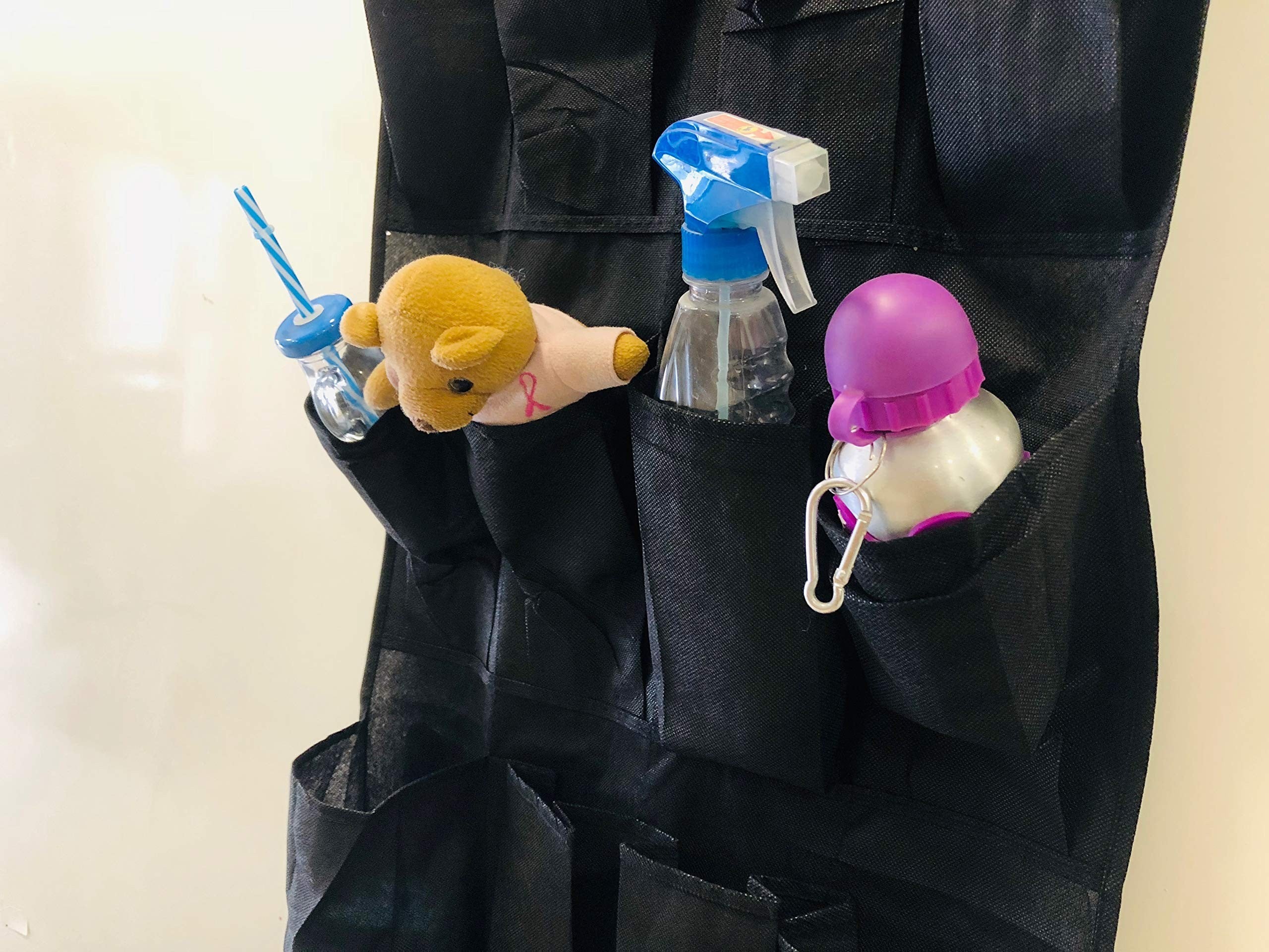 GoHooked black 20-pocket non-woven fabric door organizer with clear pockets holding a teddy bear, spray bottle, and a water bottle.