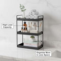 GoHooked black 3-tier standing iron rack organizer with towels, bottles, and books on a countertop.