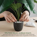 GoHooked artificial Alocasia plant with broad green leaves being arranged in a speckled black pot with decorative pebbles.
