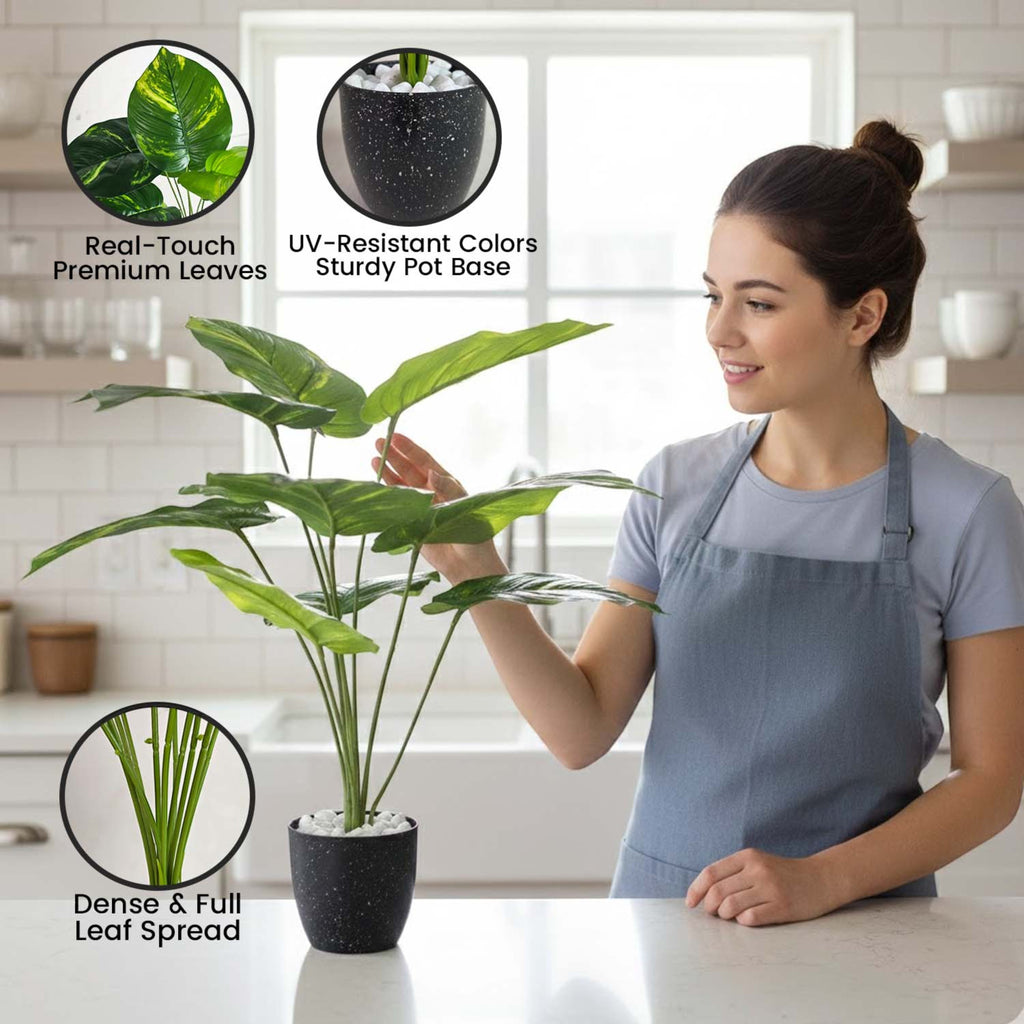 GoHooked artificial Alocasia plant with green leaves in a speckled pot, displayed by a woman in a bright kitchen.