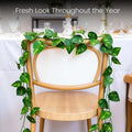 Go Hooked green artificial arrowhead leaf creeper garland draped over a wooden chair, perfect for home decor.