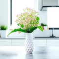 GoHooked light pink artificial baby's breath flowers in a white textured vase, with green foliage accents.