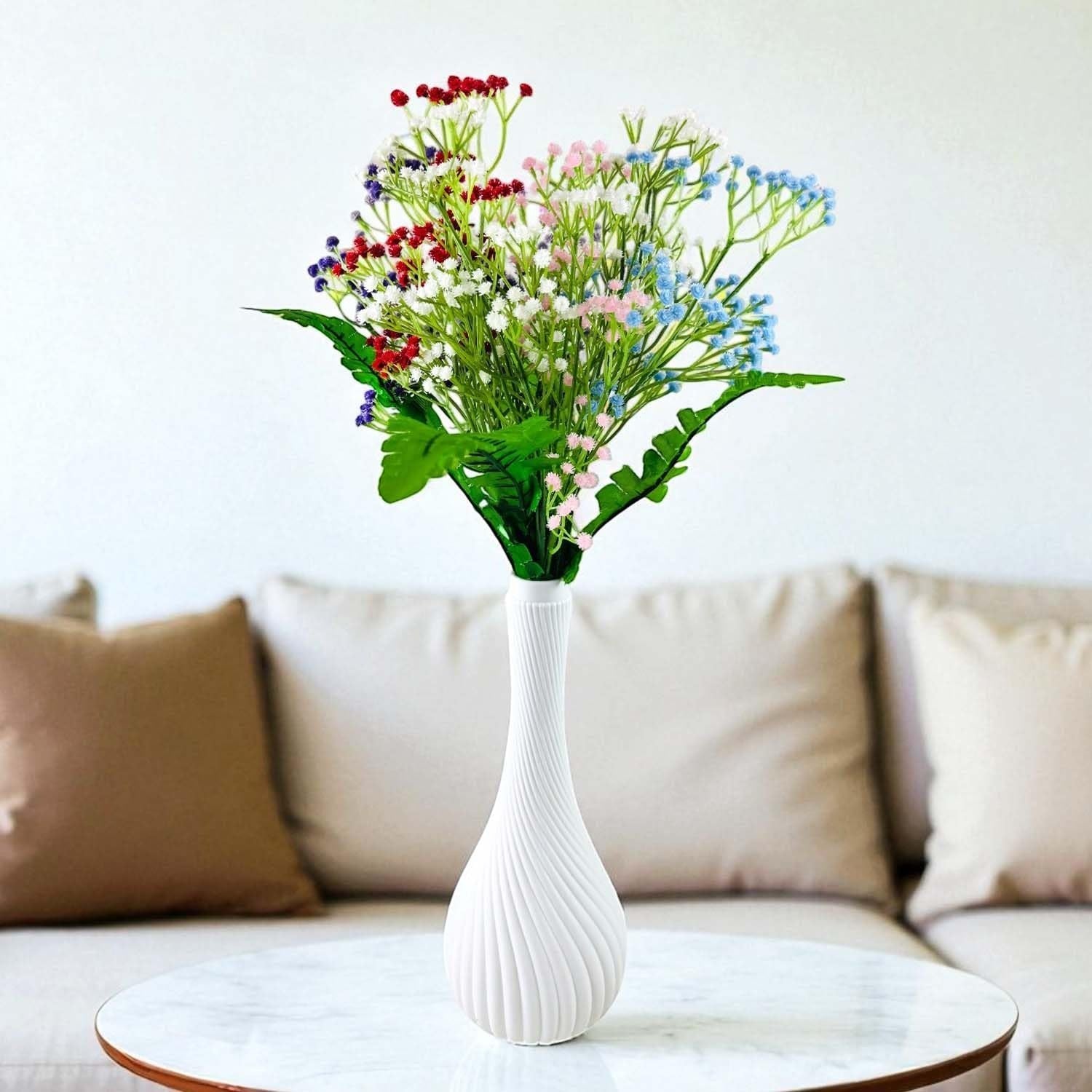 Go Hooked multicolor baby's breath artificial flowers with green fern leaves in a white Surahi vase.