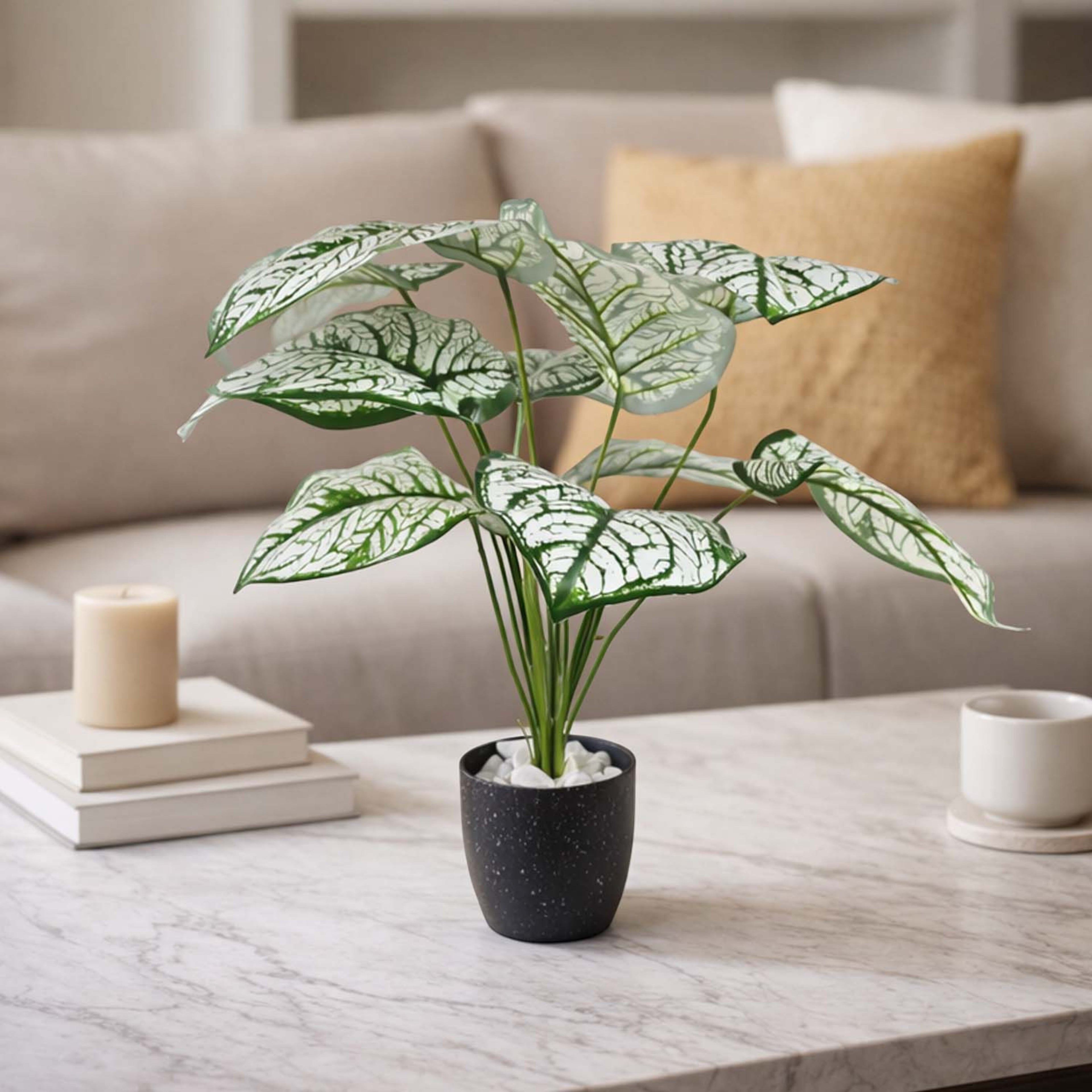 GoHooked artificial Caladium Bicolor plant with patterned green leaves in a black speckled pot on a marble table.