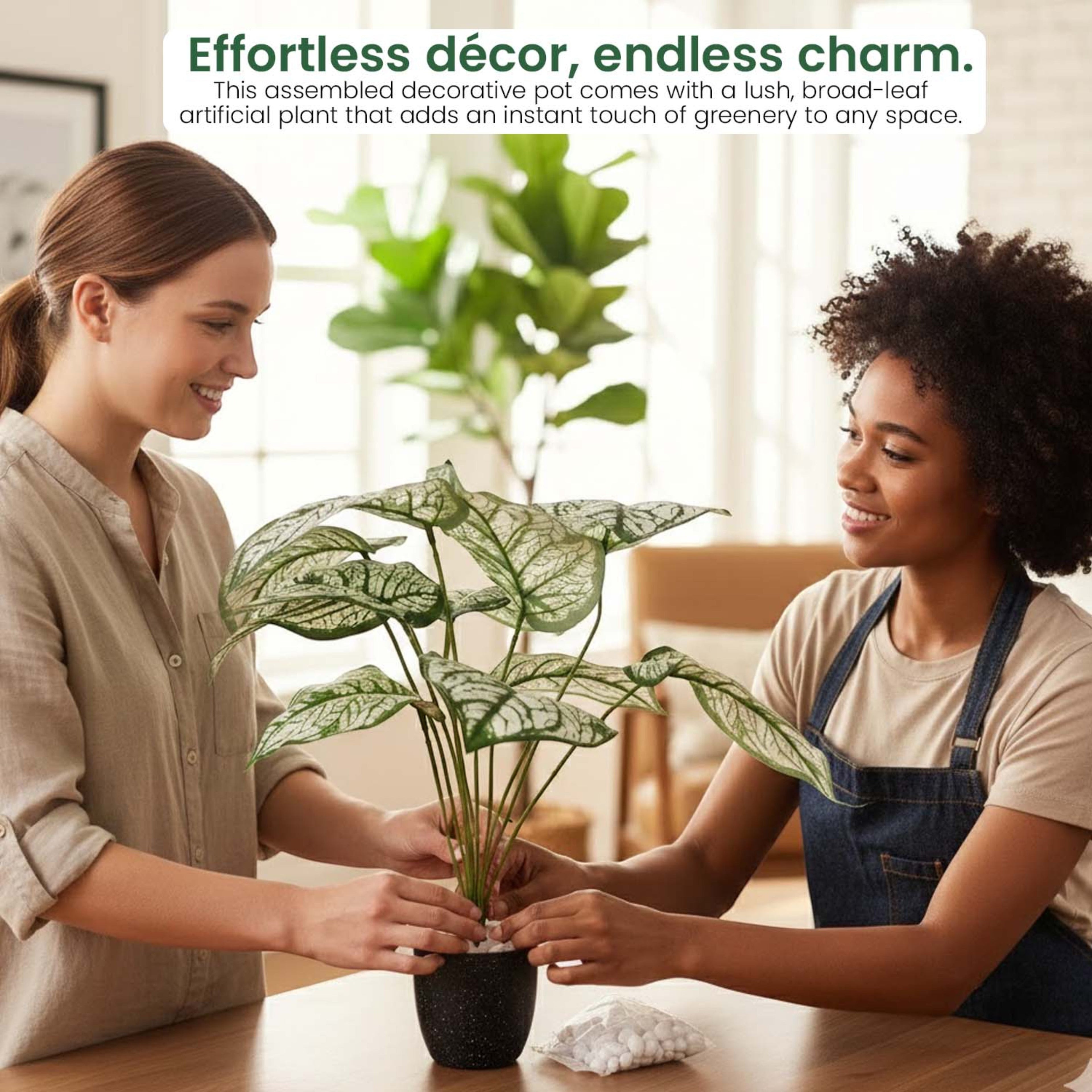 Two women arranging a GoHooked artificial Caladium plant with patterned green and white leaves in a decorative pot.