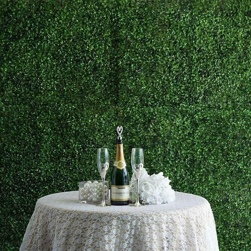 GoHooked green ivy artificial grass tiles create a lush backdrop for a table with champagne and glasses.