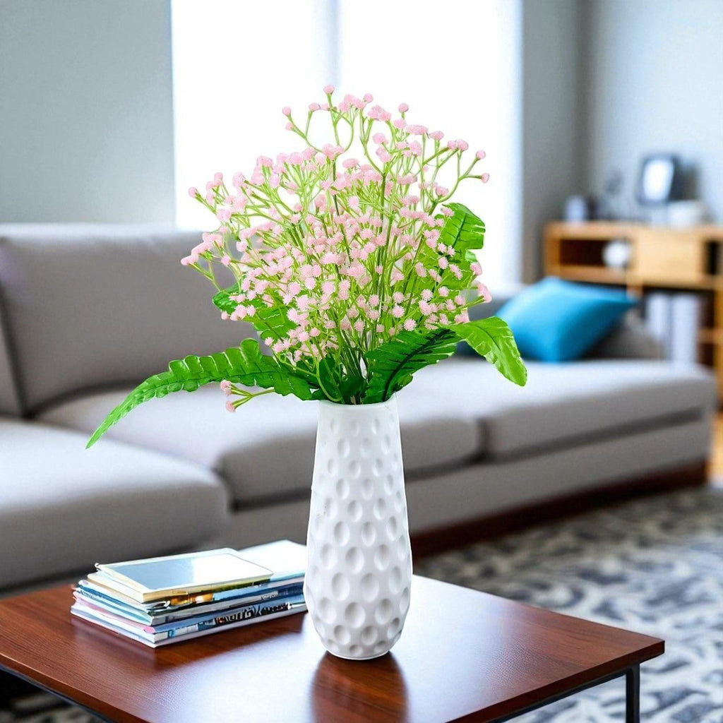Go Hooked artificial lavender baby's breath flowers with fern leaves in a white textured vase on a table.