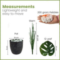 GoHooked artificial monstera plant kit with black speckled pot, green stem, 12 leaves, and decorative white pebbles.