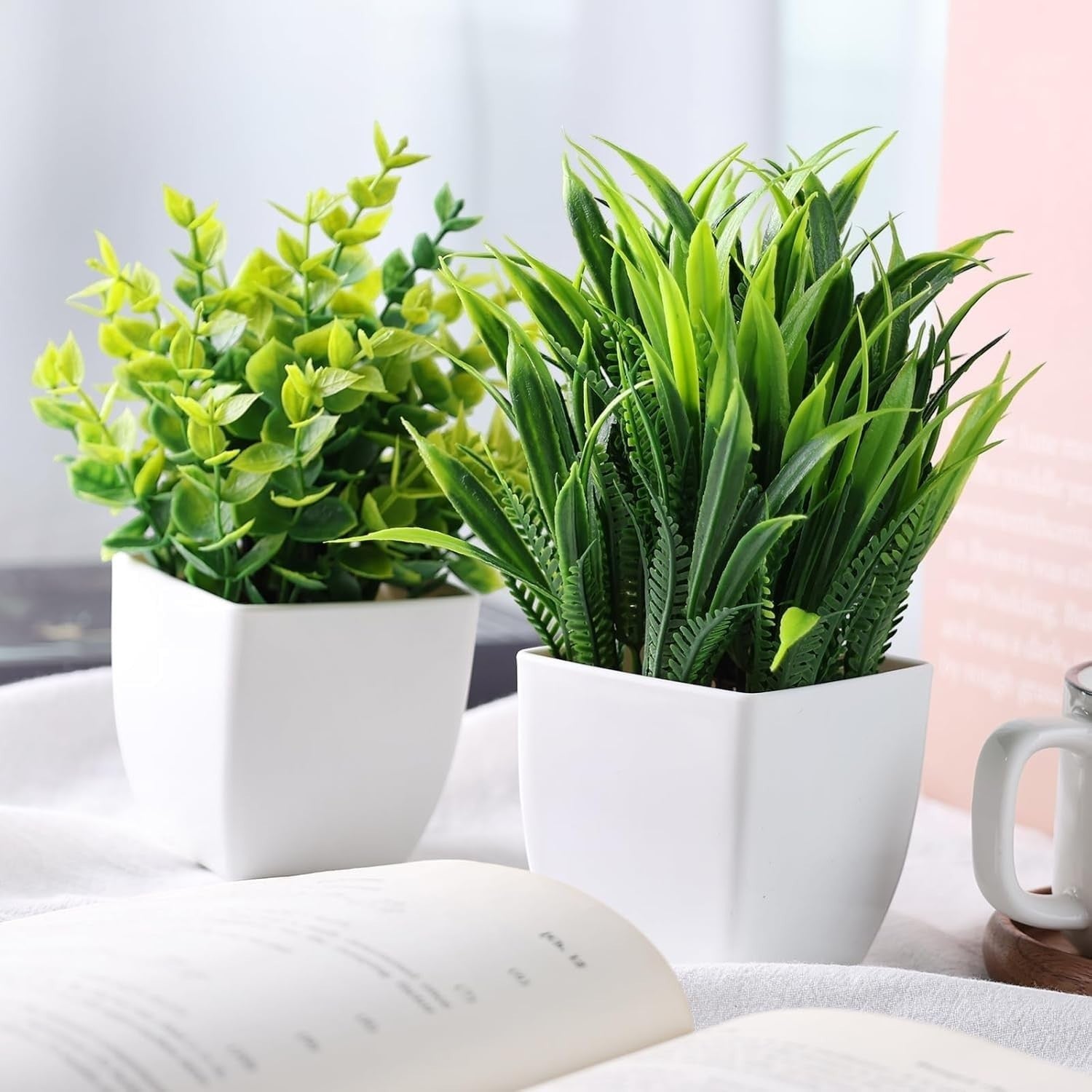 GoHooked artificial plants in white square pots, one with small green leaves, the other with spiky green foliage.