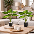 Two GoHooked artificial green potted plants with patterned leaves on a wooden coffee table in a living room.