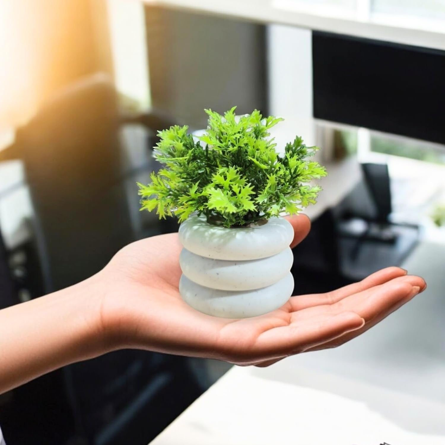 GoHooked Bianco artificial mini plant in a white stacked pot, held in a hand. Realistic green foliage.