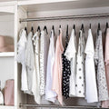 GoHooked BIANCO black plastic hangers with non-slip grooves organize a wardrobe of light-colored dresses and tops.