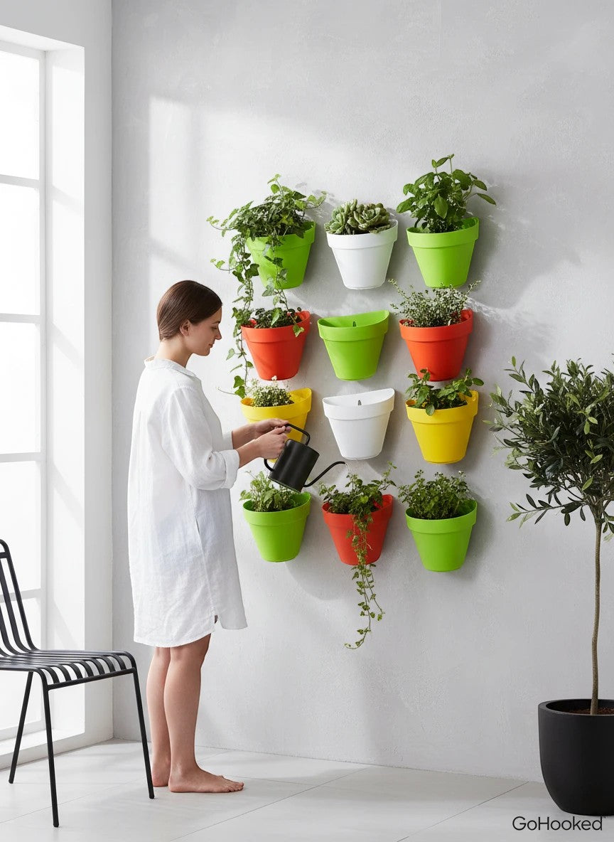 GoHooked Bianco wall hanging pots in assorted colors (green, orange, yellow, white) holding plants. Woman watering plants.