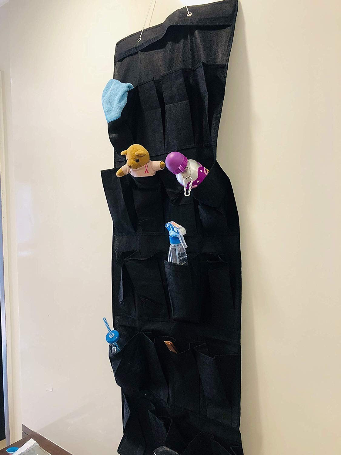 Go Hooked black 20-pocket over-the-door organizer made of non-woven fabric, holding toiletries, toys, and cleaning supplies.