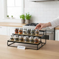 GoHooked black 3-tier wooden shelf organizer holding spice jars on a kitchen counter.