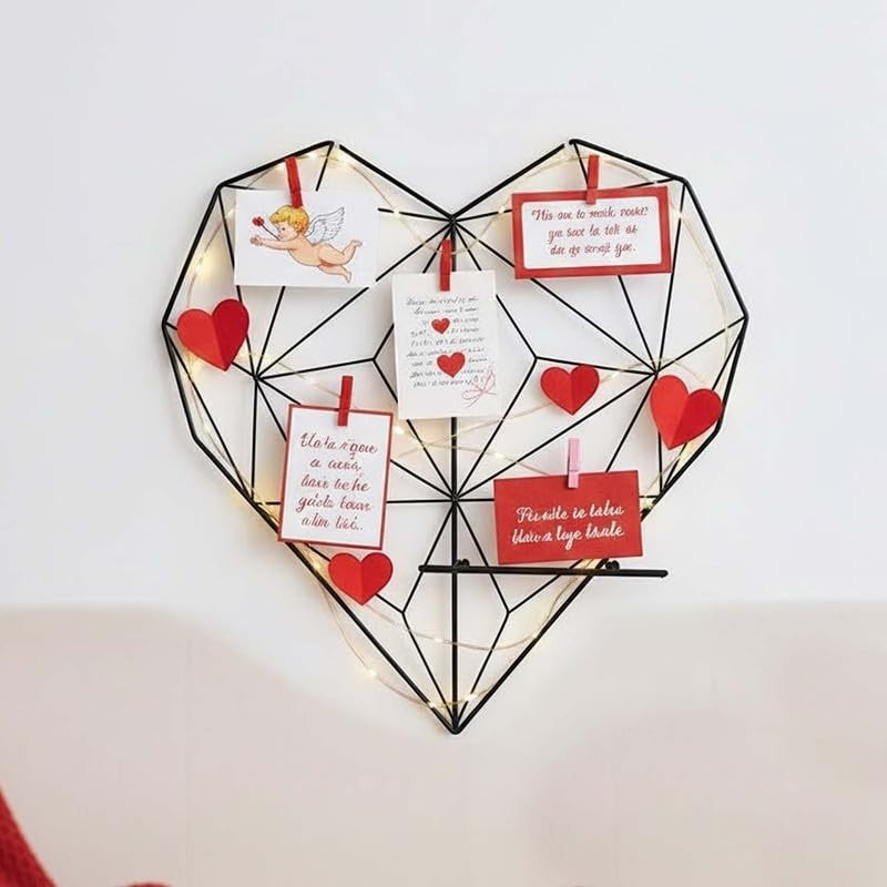 GoHooked black metal heart-shaped wall photo grid with shelf and fairy lights, ideal for displaying memories.