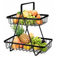 GoHooked black metal 2-tier fruit basket with handle, filled with oranges, grapes, pineapple, and lemons.