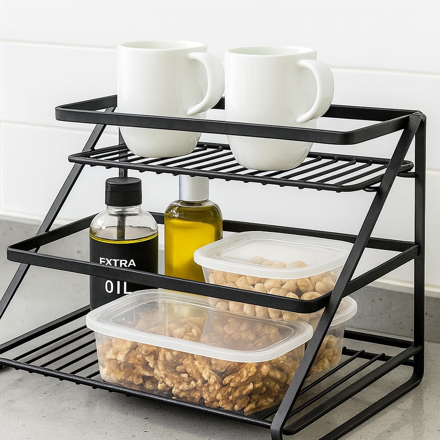 Go Hooked black metal 2-tier standing rack organizer with step shelves holding mugs, oil bottles, and food containers.