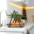Go Hooked black metal 2-tier storage basket with wooden handle, holding broccoli, tomatoes, and carrots.