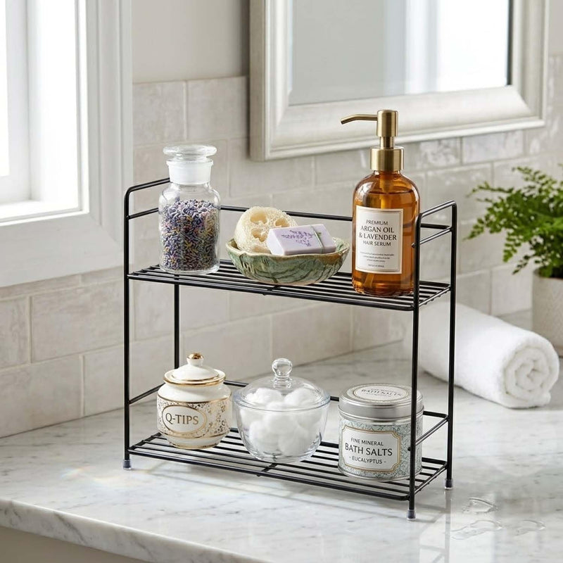 GoHooked black metal 2-tier wire rack organizer holding bathroom essentials like soap, bath salts, and cotton balls.