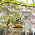 Go Hooked black metal cat-shaped bird feeder hanging from a tree branch with a bird flying towards it.