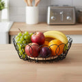 GoHooked black metal wire fruit basket with wooden base, holding apples, bananas, oranges, plums, and grapes.
