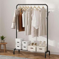GoHooked black metal freestanding garment rack with hanging rail, 8 side hooks, and bottom storage shelf holding boxes and shoes.