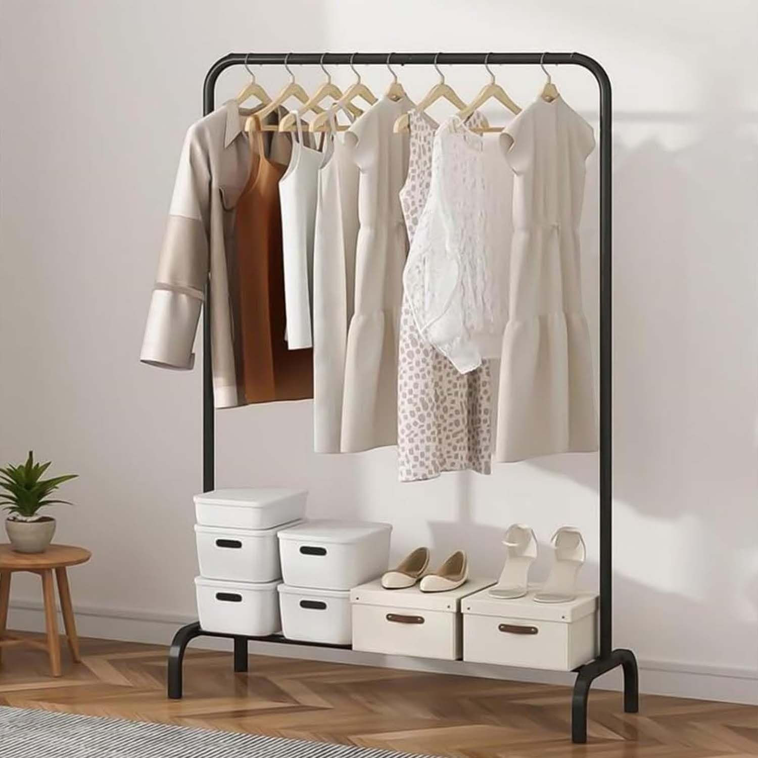 GoHooked black metal garment rack with hanging clothes and bottom shelf holding storage boxes and shoes.