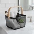 GoHooked black metal mesh storage basket with wooden handle, holding toothbrushes, towels, soap dispenser, and plant.