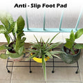 GoHooked black metal rectangular plant stand holding three potted plants on a tiled balcony.
