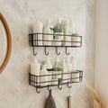 Go Hooked set of 2 black metal wall mounted storage baskets with hooks, holding toiletries and bathroom accessories.
