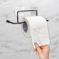 Go Hooked black rustproof metal self-adhesive toilet paper holder mounted on a marble wall.