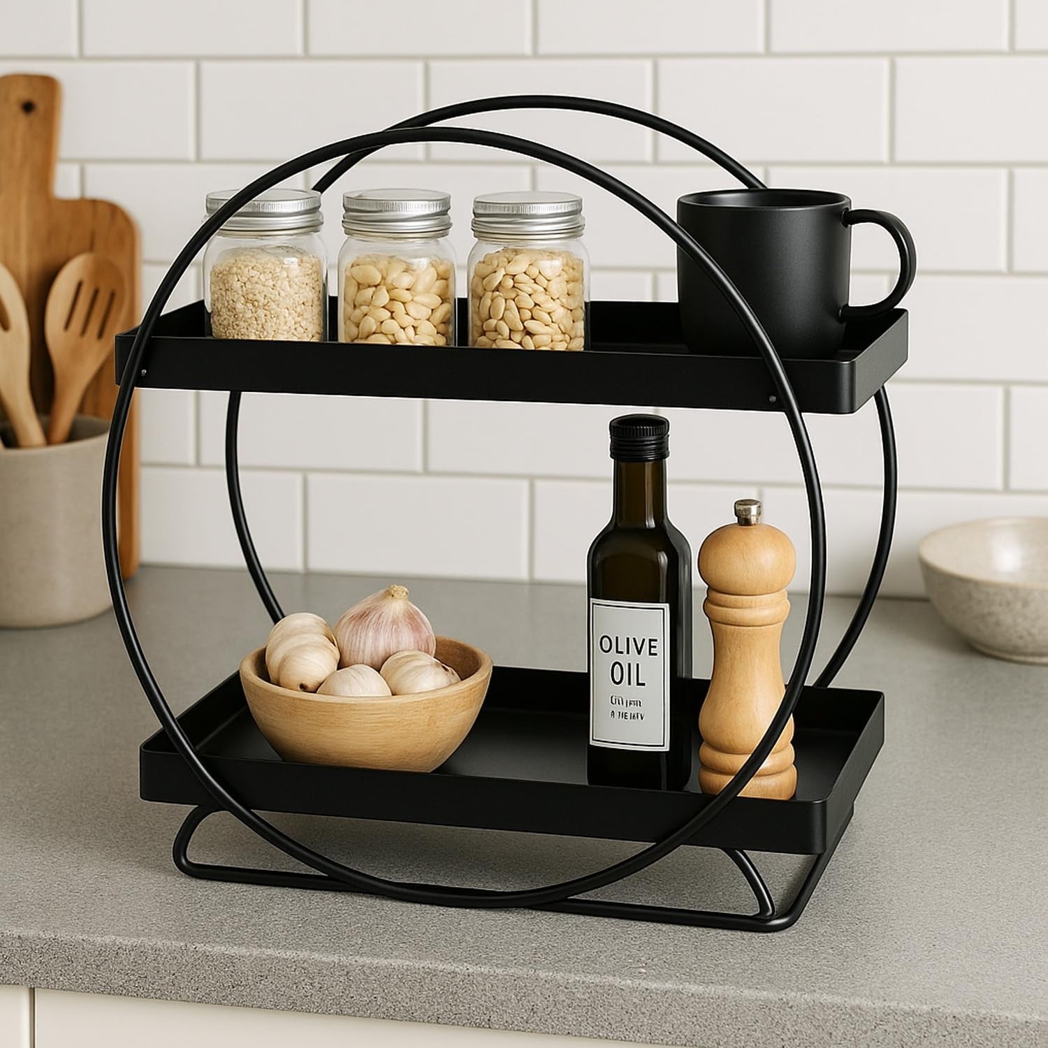 GoHooked black two-tier metal vanity storage organizer with round frame, holding jars, a mug, olive oil, and garlic.