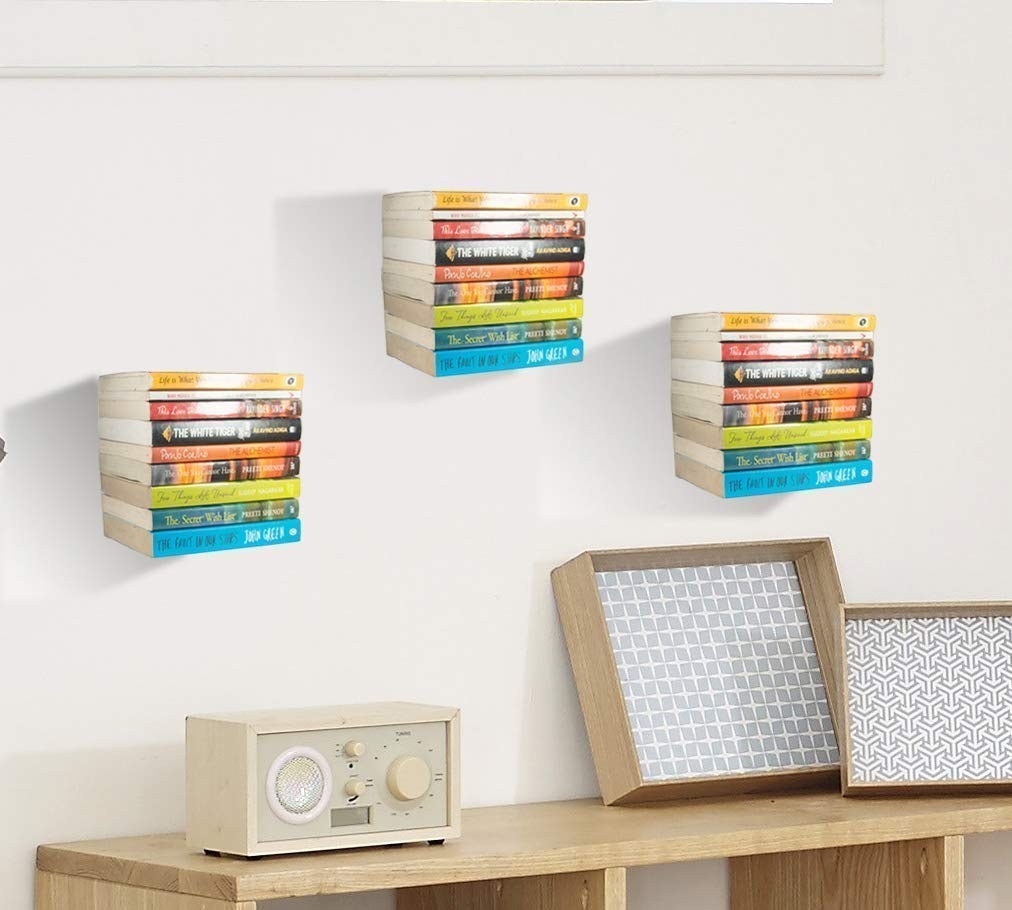 GoHooked black heavy duty iron wall mounted book shelves holding stacks of books in a living room.