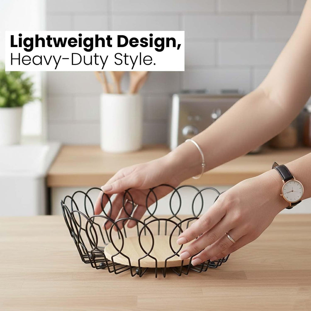 Go Hooked black metal wire fruit basket with a round wooden base, open design for airflow.