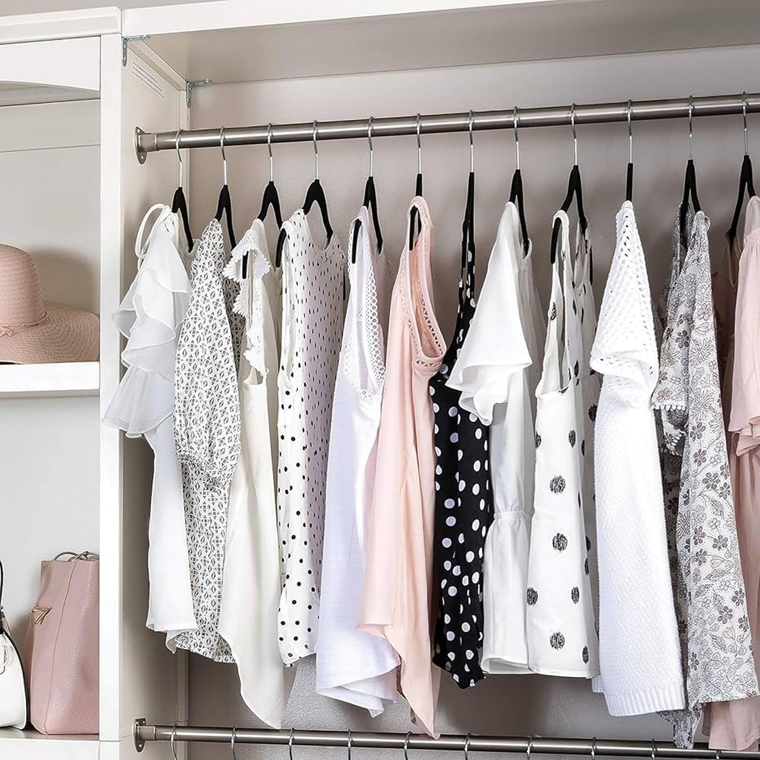 GoHooked black plastic hangers with non-slip grooves holding various women's tops and dresses in a closet.