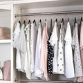 GoHooked black plastic hangers with non-slip grooves organize a wardrobe of white and pink tops.