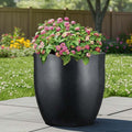 Go Hooked 22-inch black polymer planter with a modern, rounded shape, holding pink flowers. Ideal for indoor or outdoor use.