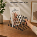 Go Hooked black coated steel triangular magazine rack holding a magazine on a wooden desk.