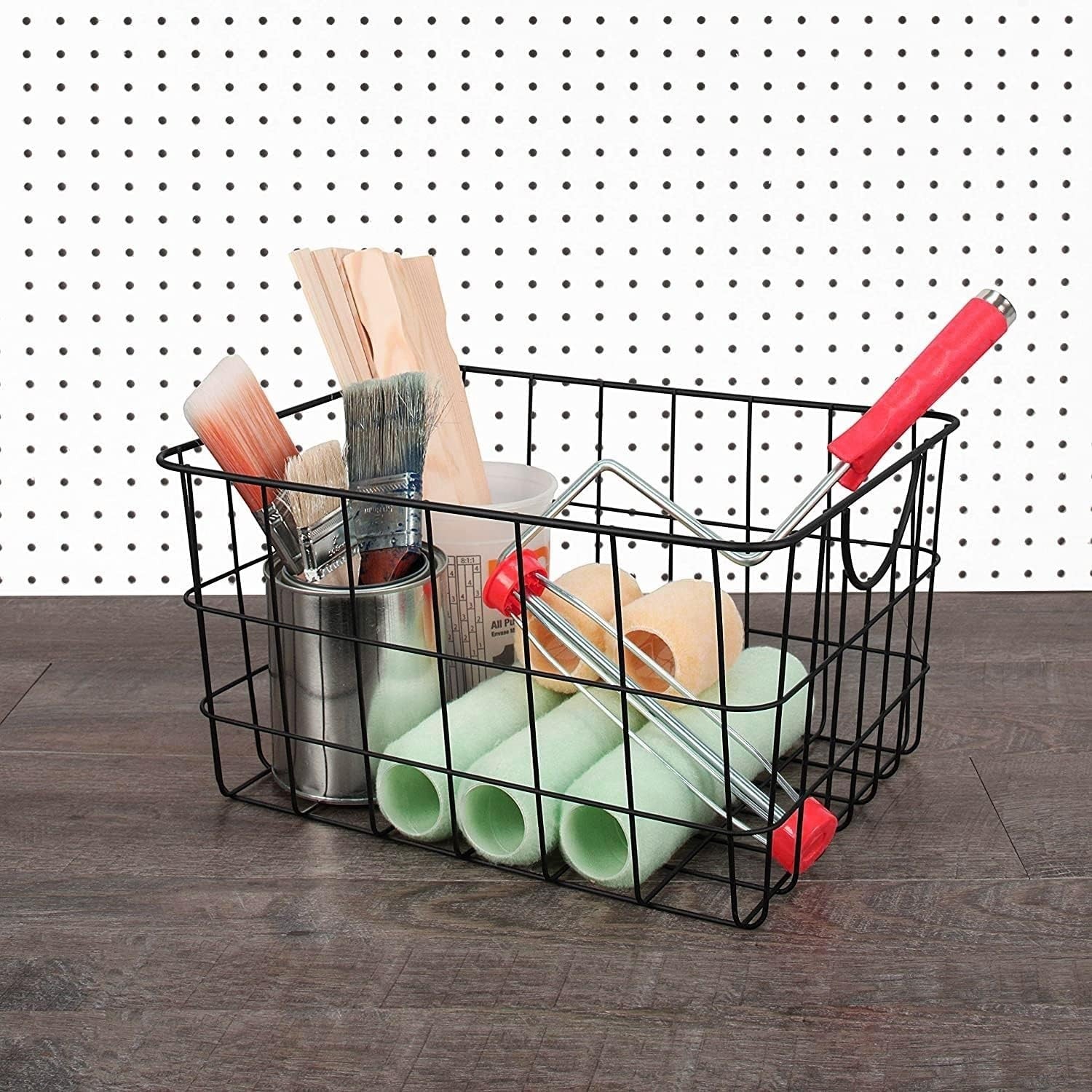 GoHooked black steel wire utility basket with curved handles, holding paint brushes, rollers, and wooden sticks.