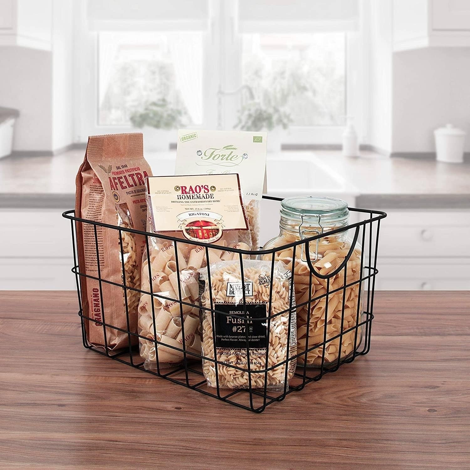Go Hooked black steel wire utility basket with curved handles, filled with pasta and pantry items.