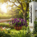GoHooked black wrought iron hanging basket bracket with ornate scrollwork, holding a coconut liner planter filled with purple petunias.