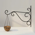 Go Hooked black wrought iron hanging planter bracket with decorative scrolls, holding a coconut coir basket.