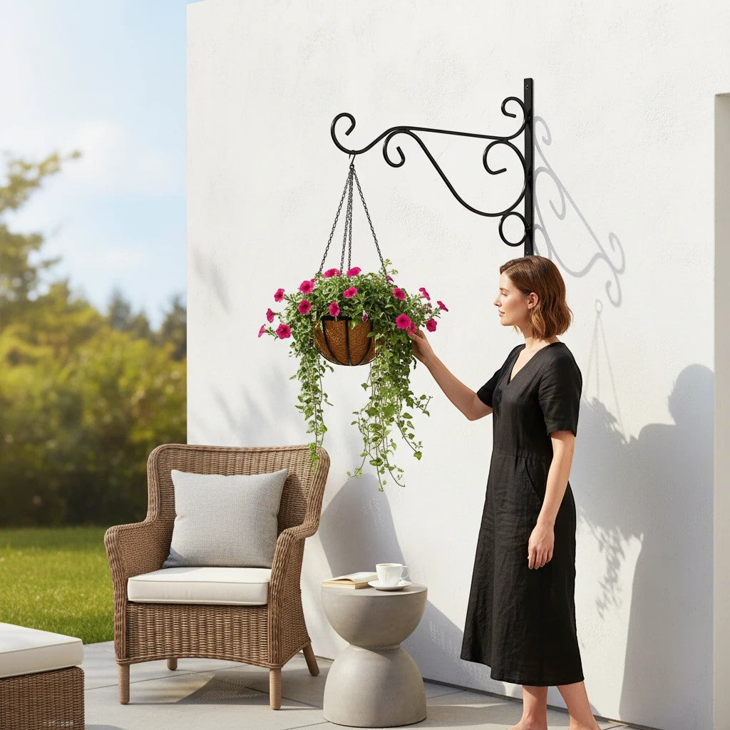 Go Hooked black wrought iron hanging planter bracket with a basket of pink flowers.