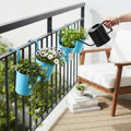 Go Hooked blue metal hanging planters with flowers and ivy on a balcony railing.