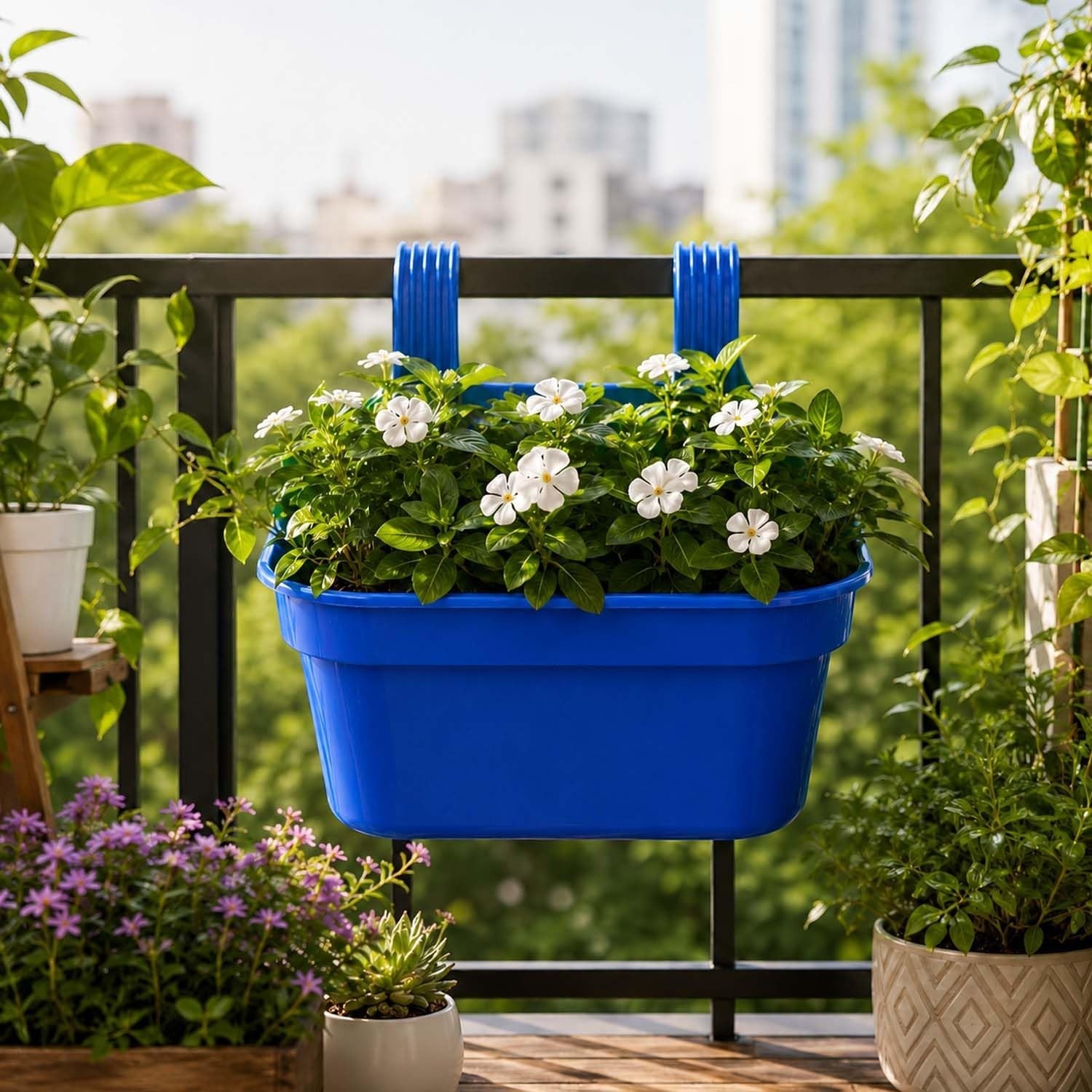 GoHooked blue plastic railing hanging planter pot with white flowers, ideal for balconies and fences.
