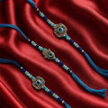 GoHooked set of 3 blue designer rakhis with evil eye and hamsa charms, pearl and blue beads, and tassel ends.
